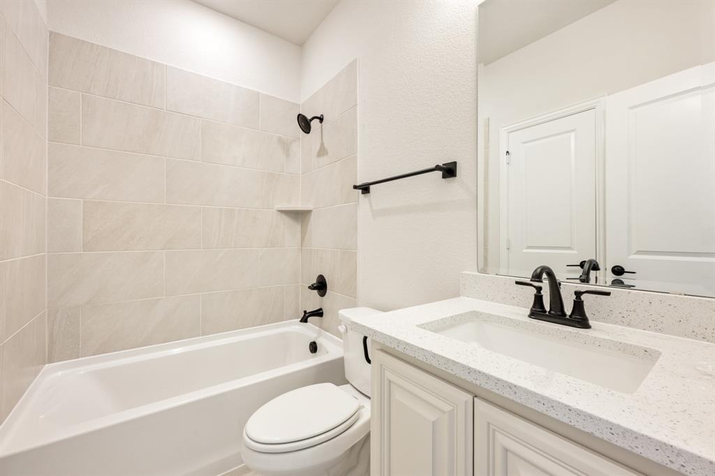 11716 Flathead Court Godley, TX 76044 - Photo 10 of 40 a bathroom with a sink a toilet a mirror a bathtub and shower