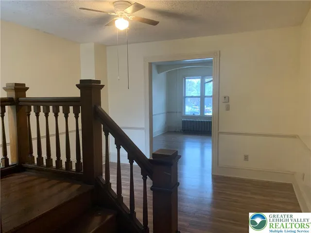 a view of a hallway with wooden floor and stairs