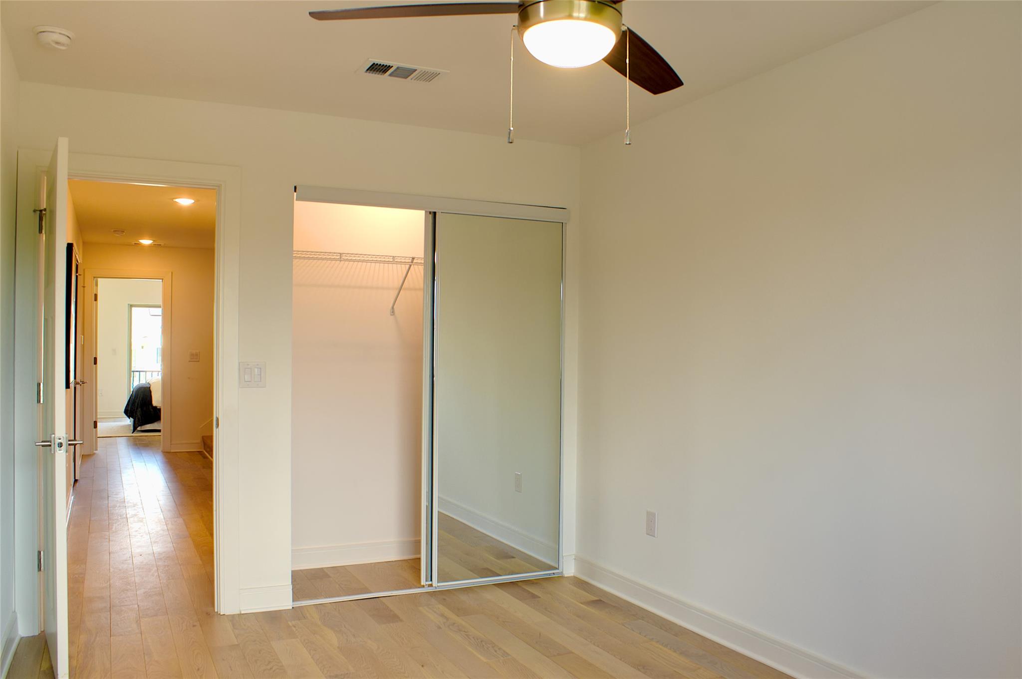 300 Tesla Circle Austin, TX 78681 - Photo 13 of 39 Room with wood-finish flooring, a ceiling fan with integrated lighting, and a mirrored sliding closet door