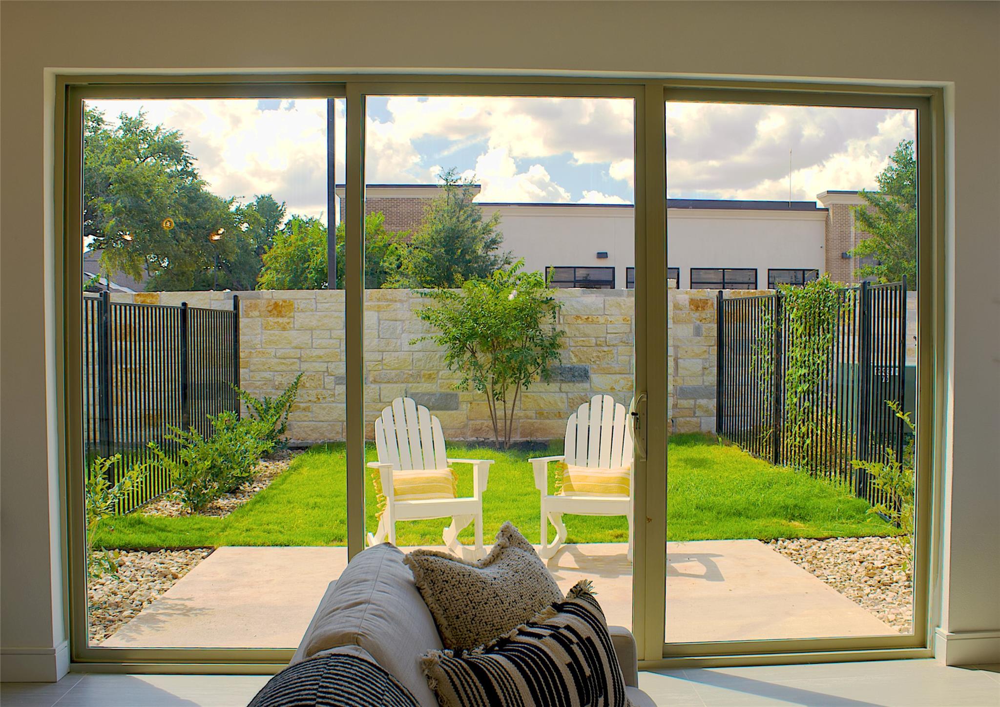 300 Tesla Circle Austin, TX 78681 - Photo 35 of 39 Expansive sliding glass doors overlook a private outdoor space featuring a stone wall, manicured lawn, and paved walkway with gravel accents