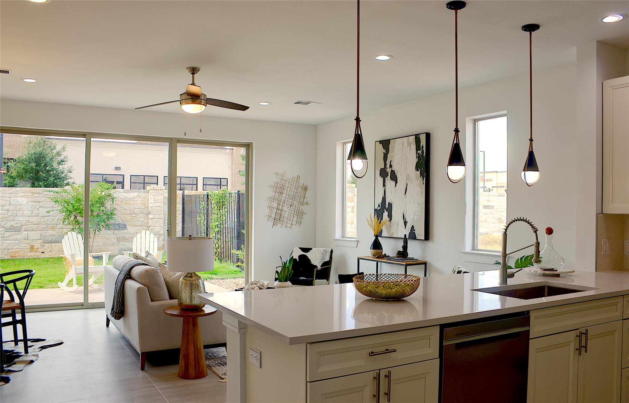 300 Tesla Circle Austin, TX 78681 - Photo 5 of 39 Spacious open-concept interior featuring light-toned flooring, a kitchen island with pendant lighting, and a built-in sink with a gooseneck faucet