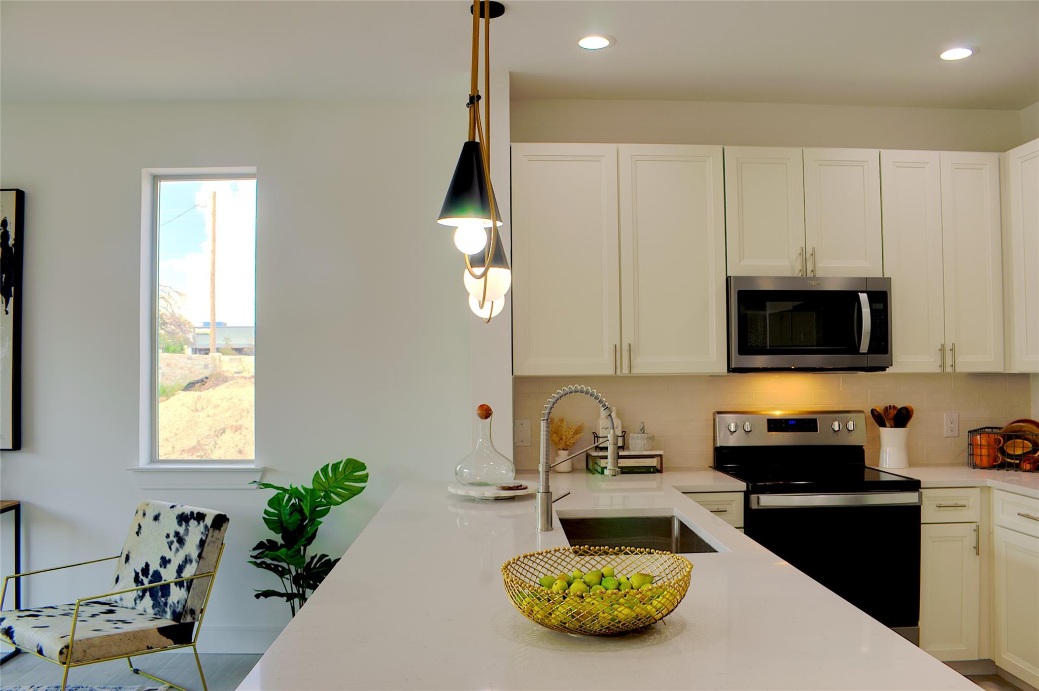 300 Tesla Circle Austin, TX 78681 - Photo 6 of 39 Modern kitchen featuring white shaker cabinetry, stainless steel appliances, a white solid surface countertop island with an undermount sink, and contemporary pendant lighting