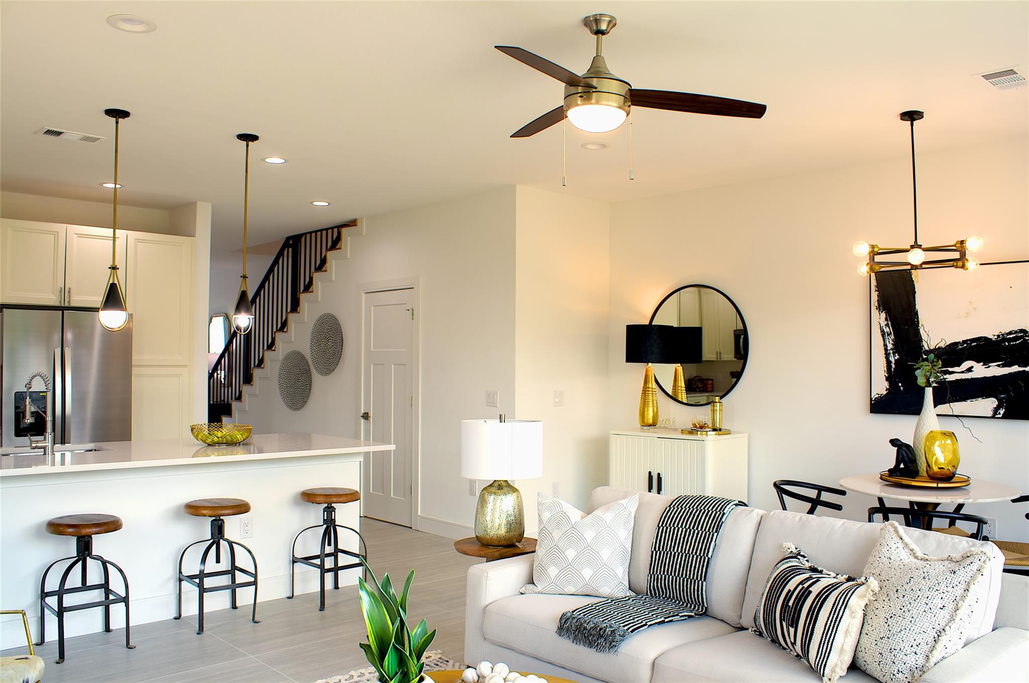 300 Tesla Circle Austin, TX 78681 - Photo 10 of 39 Open-concept living space featuring a kitchen island with pendant lighting, a ceiling fan, and a staircase with dark banisters