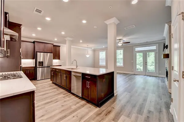 a large kitchen with stainless steel appliances kitchen island granite countertop a large counter top and wooden floors