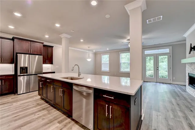 a kitchen with stainless steel appliances granite countertop a sink wooden cabinets and wooden floor