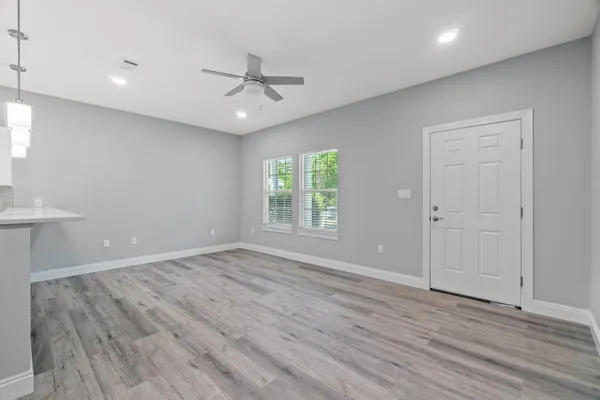 an empty room with wooden floor fan and windows