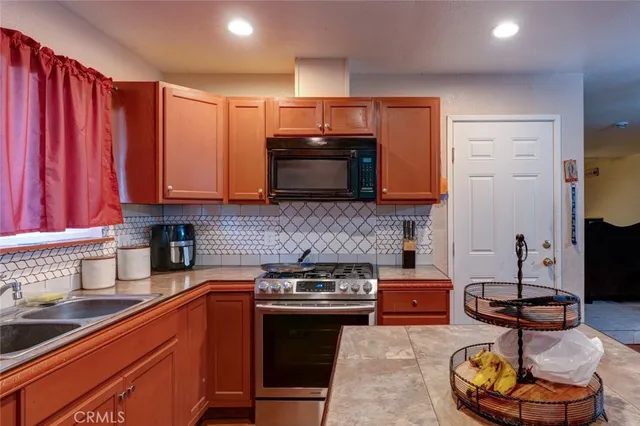 a kitchen with stainless steel appliances granite countertop a stove a sink and a microwave