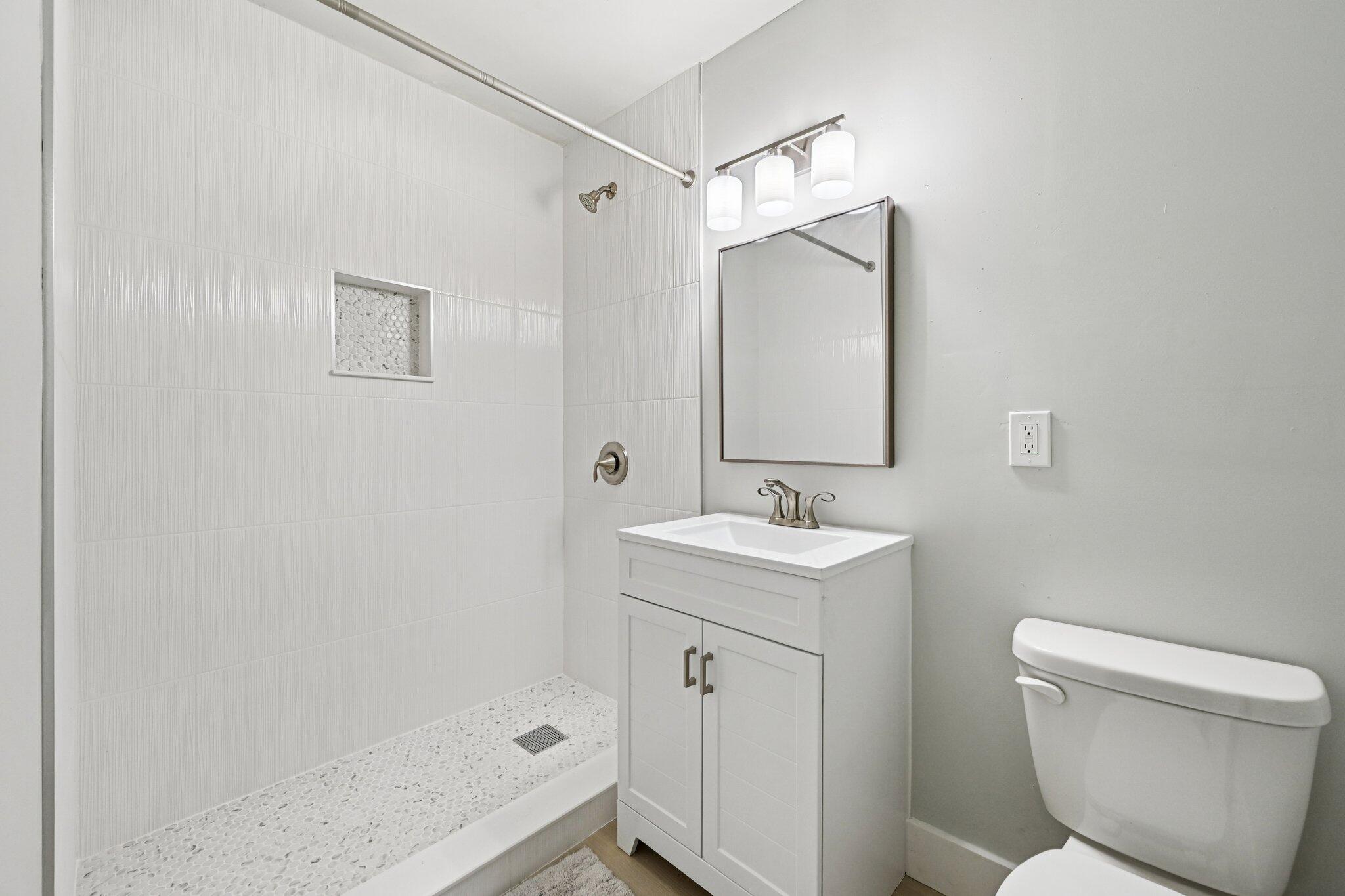 5852 Southeast Wesley Avenue Stuart, FL 34997 - Photo 2 of 27 a bathroom with a sink a toilet and shower