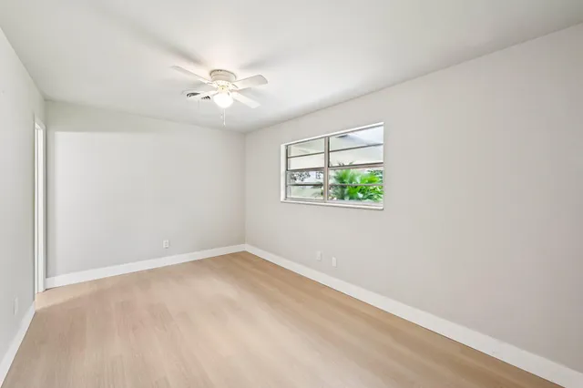 an empty room with windows and fan