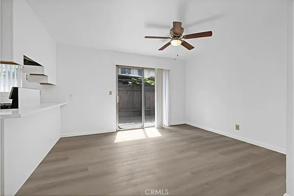 a view of empty room with wooden floor and ceiling fan
