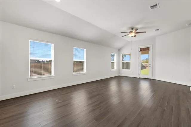 a view of an empty room with a window and wooden floor