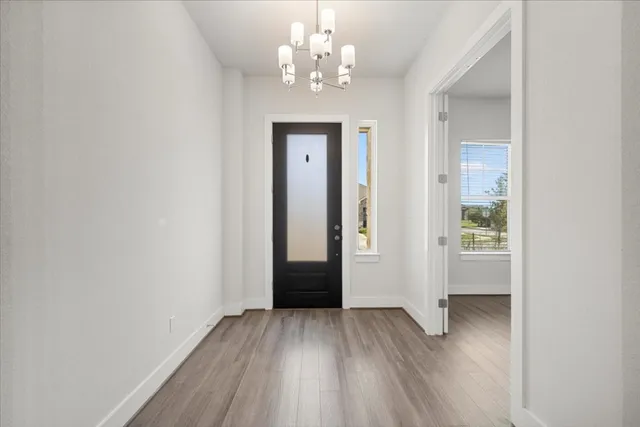 a view of a hallway with wooden floor and a chandelier
