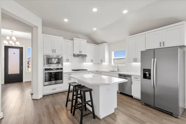 a kitchen with stainless steel appliances a refrigerator a stove a sink and white cabinets