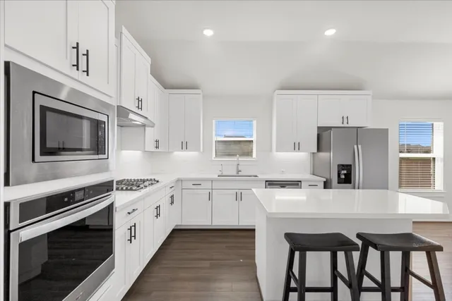 a kitchen with stainless steel appliances a stove a sink island and a refrigerator