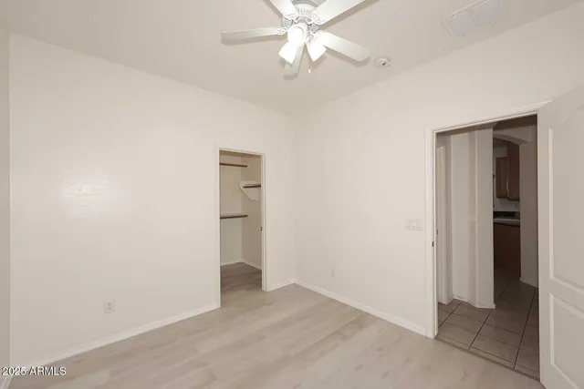 an empty room with closet and a ceiling fan