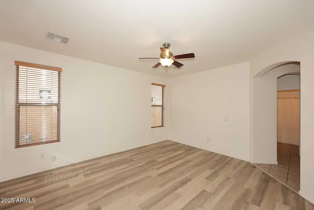 a view of empty room with wooden floor and fan