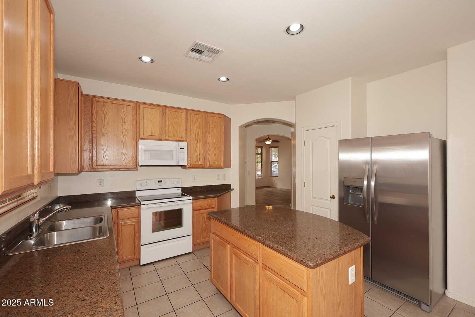 2710 East Chester Drive Chandler, AZ 85286 - Photo 8 of 28 a kitchen with stainless steel appliances granite countertop a sink a stove and a refrigerator