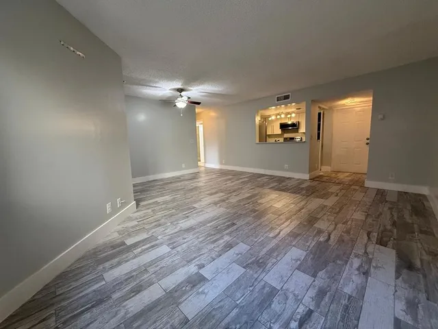 an empty room with wooden floor cabinet and windows