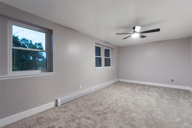 an empty room with a window and a ceiling fan