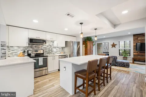 a kitchen with stainless steel appliances kitchen island granite countertop a stove a refrigerator a kitchen island a dining table and chairs with wooden floor