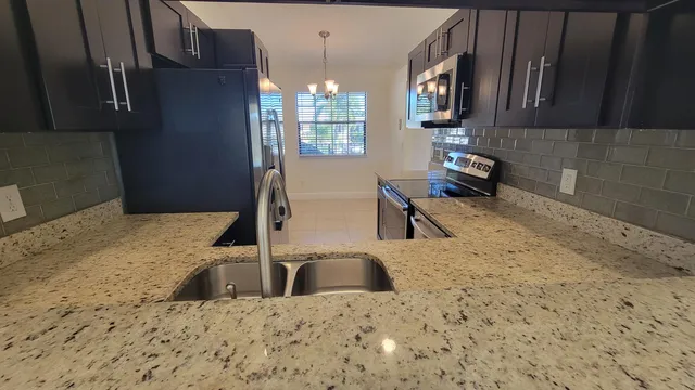 a kitchen with granite countertop a sink a stove and a refrigerator