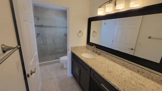 a bathroom with a granite countertop sink toilet and shower