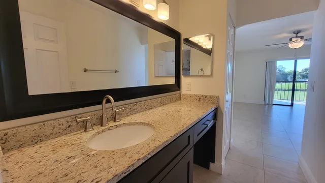a bathroom with a granite countertop sink and a mirror