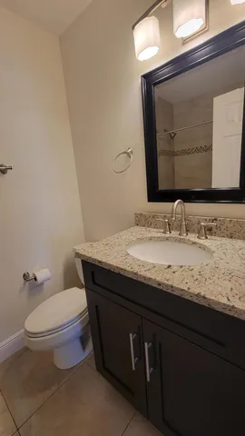 a bathroom with a granite countertop toilet sink and mirror