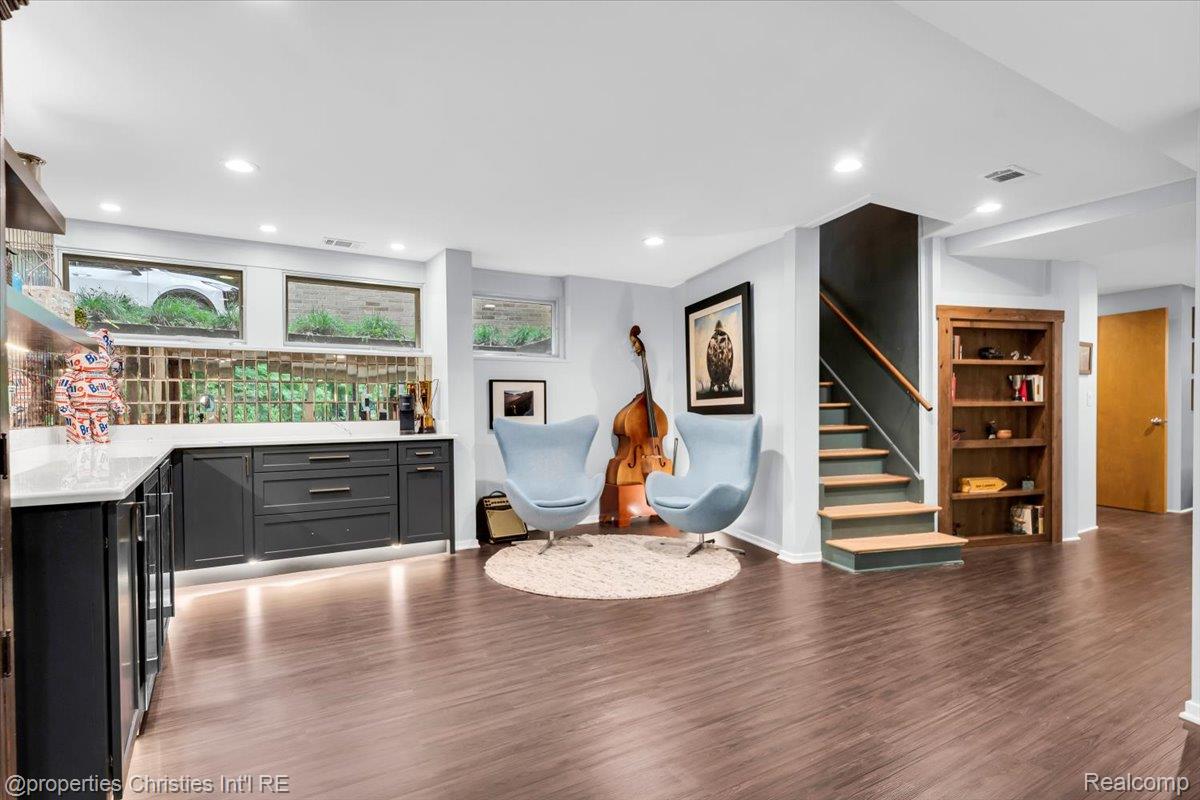 3939 Charing Cross Road Bloomfield Hills, MI 48304 - Photo 29 of 33 Spacious finished lower level featuring wood-finish flooring, a built-in wet bar with white countertops, mirrored backsplash, and under-cabinet lighting