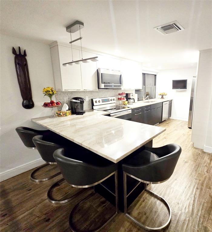 1401 North Riverside Drive, Unit 707 Pompano Beach, FL 33062 - Photo 7 of 32 a kitchen with granite countertop a table chairs and a wooden floor