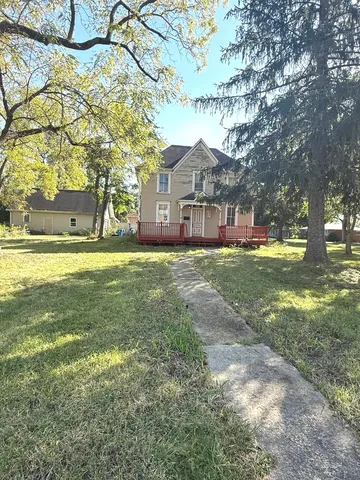 a view of a big house with a big yard and large trees