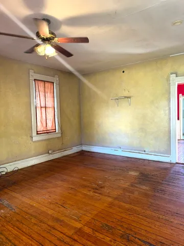 a view of a room with wooden floor and a ceiling fan