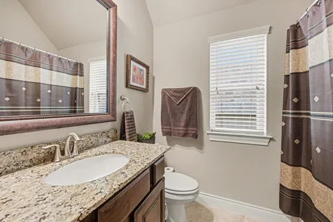 a bathroom with a granite countertop sink toilet and shower