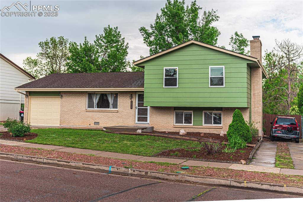 1917 Wooten Road Colorado Springs, CO 80915 - Photo 3 of 35 a front view of a house with a garden and plants