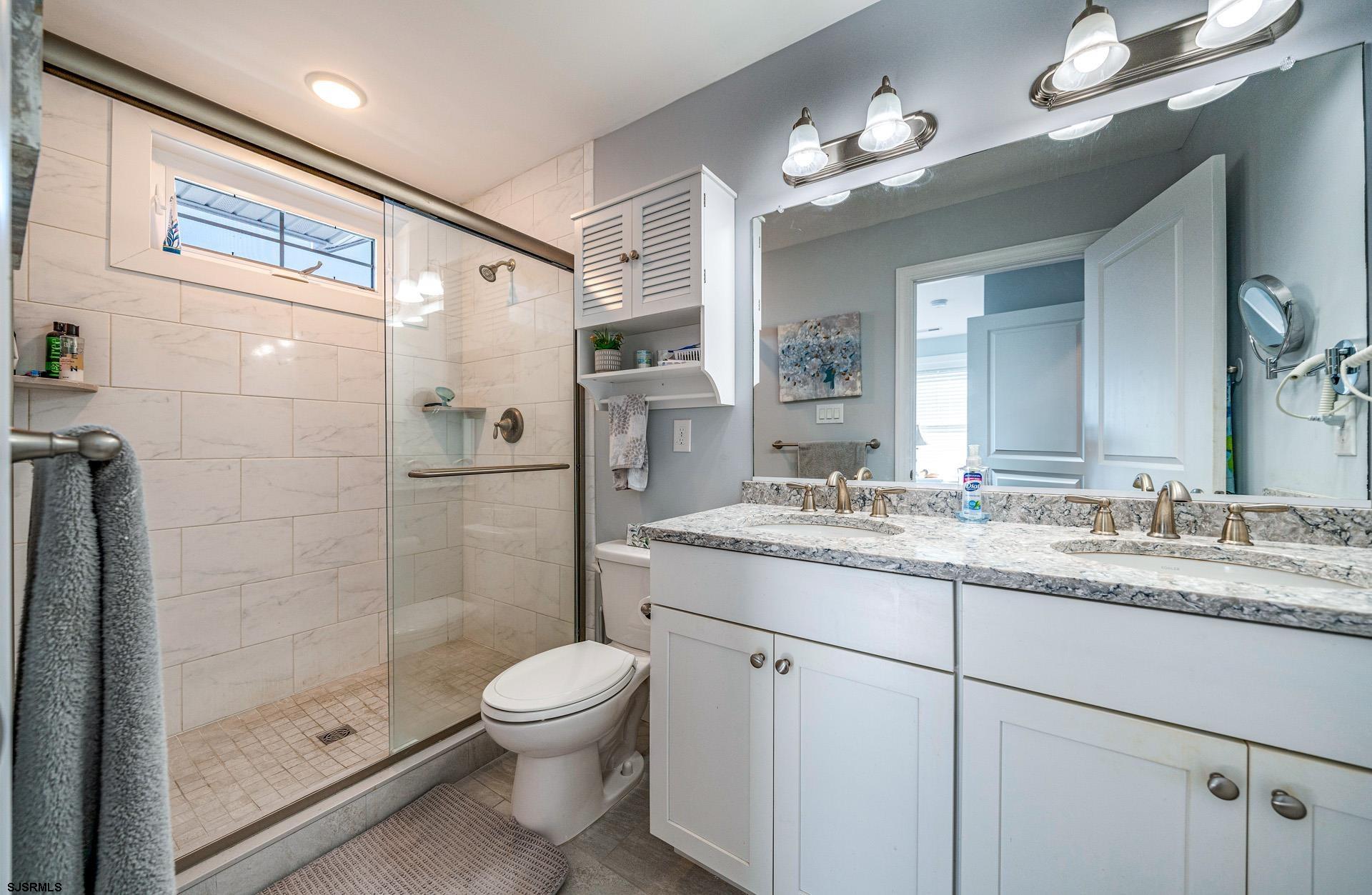 225 West Inlet Road Ocean City, NJ 08226 - Photo 19 of 56 a bathroom with a granite countertop shower sink mirror and toilet