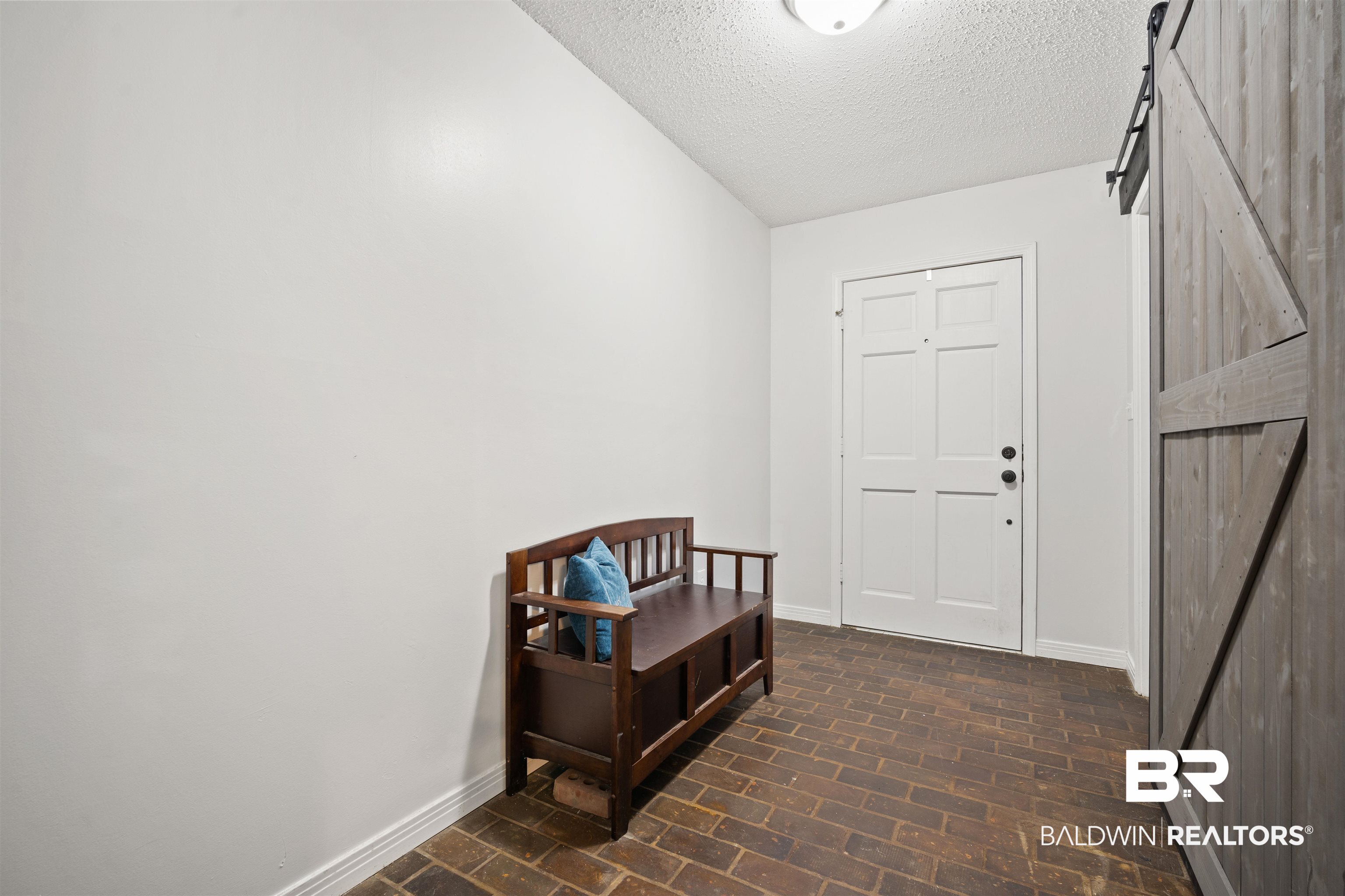 7807 Yorkhaven Road Mobile, AL 36695 - Photo 26 of 34 Entrance foyer with a barn door, brick flooring, and a textured ceiling