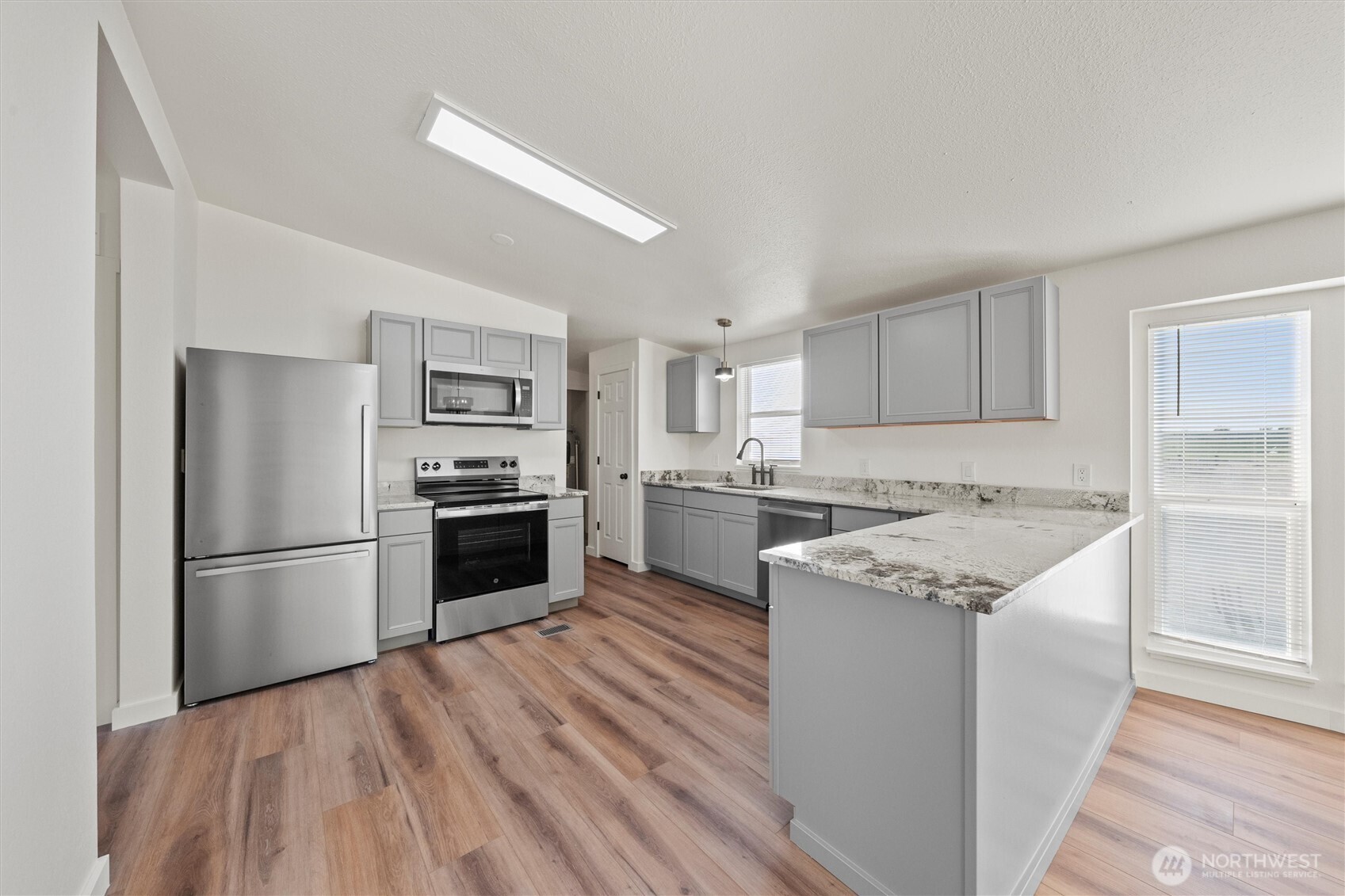2326 Stoneridge Road Northeast Moses Lake, WA 98837 - Photo 13 of 37 a kitchen with a refrigerator stove and white cabinets