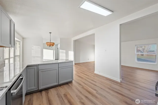 a kitchen with granite countertop white cabinets and wooden floor