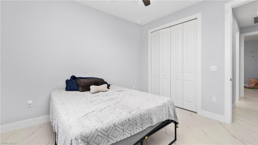 4571 22nd Street Northeast Naples, FL 34120 - Photo 22 of 47 Bedroom with a closet, light marble finish floors, and a ceiling fan
