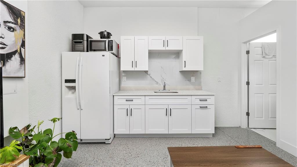 4571 22nd Street Northeast Naples, FL 34120 - Photo 25 of 47 Kitchen with white cabinetry, white refrigerator with ice dispenser, dark speckled floor, and light stone counters