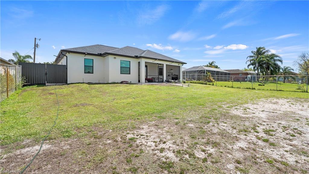 4571 22nd Street Northeast Naples, FL 34120 - Photo 40 of 47 Back of house with stucco siding, a sunroom, a fenced backyard, ceiling fan, and a patio