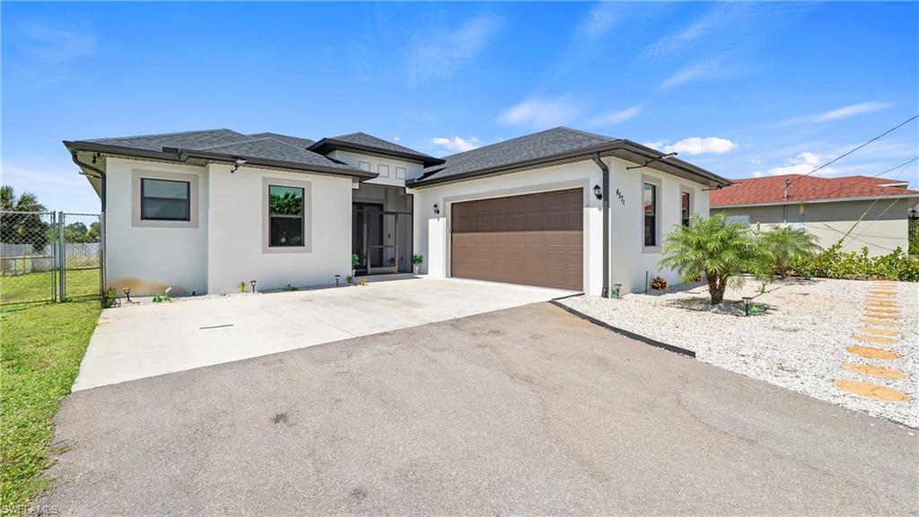 4571 22nd Street Northeast Naples, FL 34120 - Photo 6 of 47 View of front facade featuring concrete driveway, a garage, stucco siding, a gate, and roof with shingles