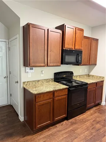 a kitchen with granite countertop wooden cabinets and a stove top oven