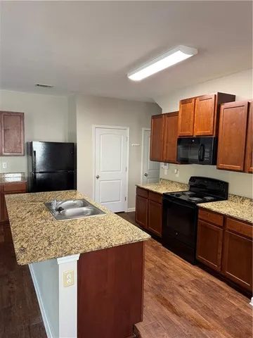 a kitchen with kitchen island granite countertop a sink stove and refrigerator