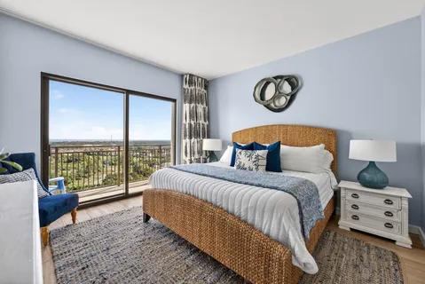 a bedroom with a bed a lamp and a large window