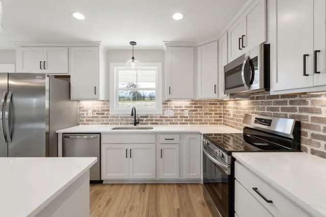 a kitchen with stainless steel appliances granite countertop a sink stove microwave and refrigerator
