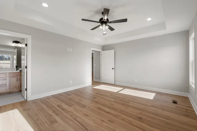 a view of an empty room with wooden floor and a ceiling fan