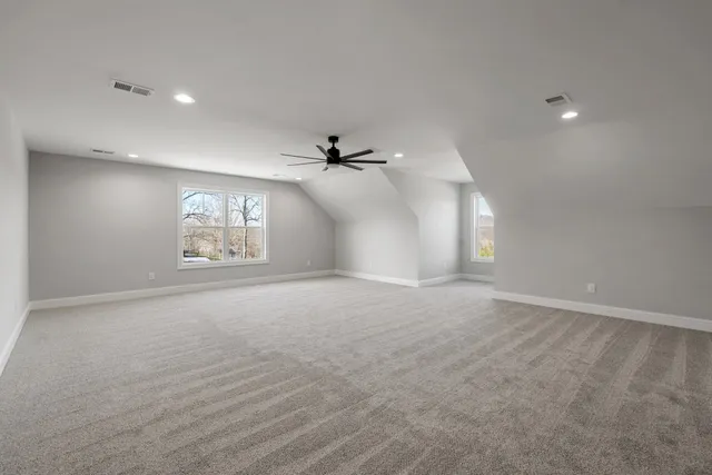 an empty room with windows and ceiling fan