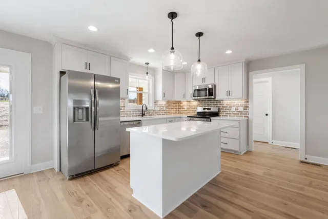 a kitchen with stainless steel appliances granite countertop a refrigerator a sink a stove and a oven