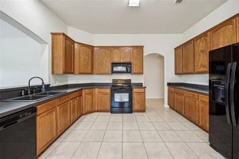 a kitchen with stainless steel appliances granite countertop a stove top oven a sink dishwasher and a refrigerator
